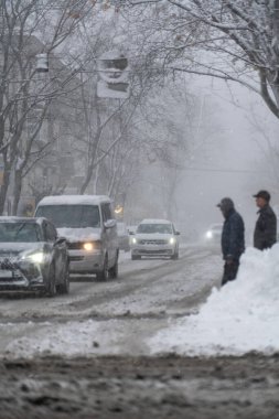 Snowy city street with cars in traffic, winter day