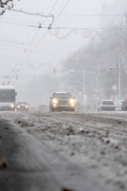 Snowy city street with cars in traffic, winter day