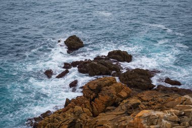 Atlantik Okyanusu 'nun küçük dalgaları kıyıdaki kayalara çarpar.