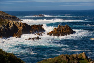 Kıyı kayalarına vuran beyaz köpüklü kaynayan uzun okyanus dalgaları (deniz manzarası))