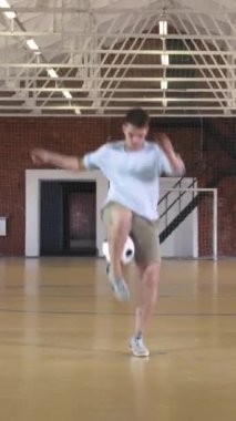 Futbol serbest stili. Genç adam futbol topuyla pratik yapıyor. Dikey video