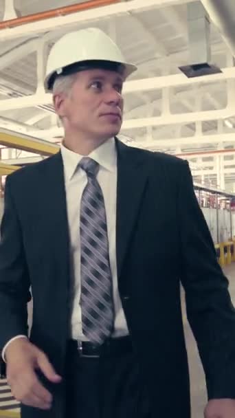 ハード帽子工場を歩くと彼の時計を見てビジネスマン 垂直ビデオ — ストック動画