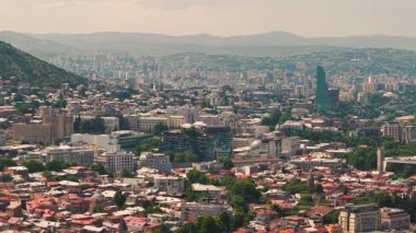 Tarihi binalar, modern kuleler ve yeşil tepelerle orta Tiflis 'in manzarası