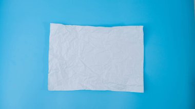 Kağıt bir top mavi arka planda boş bir sayfaya yayılır. Metin veya reklam alanı için kopyalama alanı olan buruşturulmuş boş beyaz kağıt.