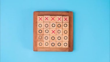 Tahta oyun tahtası tic-tac-toe. Mavi arka planda X-O ve ortadaki harflerin dönüşümü birbirinden farklı..