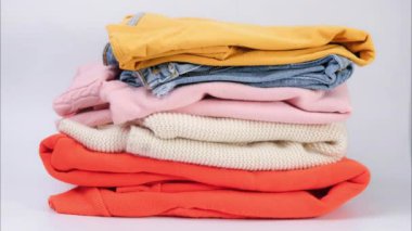 Beyaz arka plandaki renkli kıyafet yığınlarının hareketini durdur. Bağış veya alışveriş için kıyafetler. Ev çamaşırları..