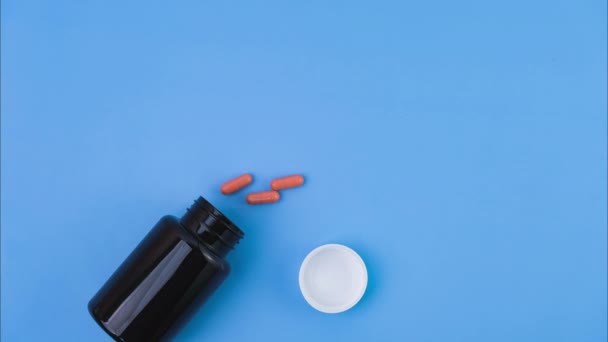 Kapsul Pil Menuangkan Dari Botol Farmasi Latar Belakang Biru Konsep — Stok Video