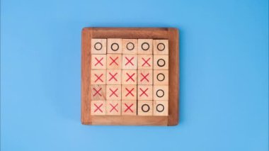 Tahta masa tic-tac-toe 'nun hareketli animasyonunu durdurun. Mavi arka planda X-O ve ortadaki harflerin dönüşümü birbirinden farklı..