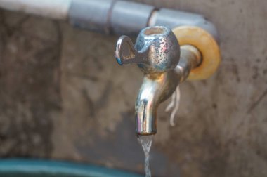 Su eski paslı demir musluktan geliyor.