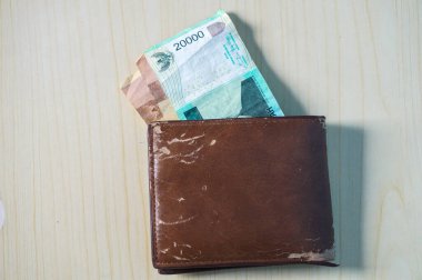 Ahşap arka planda kahverengi cüzdanlı Rupiah banknotu. Para fotoğrafı konsepti.