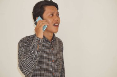 Cep telefonuyla arayan Asyalı genç adam gülümsüyor.