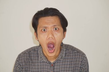 Beyaz arka planda izole edilmiş siyah gömlekli genç Asyalı adamın yüzü şaşırtıcıydı..