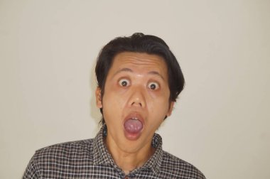 Beyaz arka planda izole edilmiş siyah gömlekli genç Asyalı adamın yüzü şaşırtıcıydı..