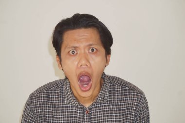 Beyaz arka planda izole edilmiş siyah gömlekli genç Asyalı adamın yüzü şaşırtıcıydı..