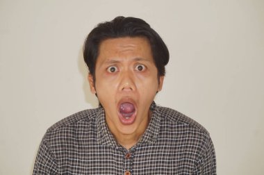 Beyaz arka planda izole edilmiş siyah gömlekli genç Asyalı adamın yüzü şaşırtıcıydı..