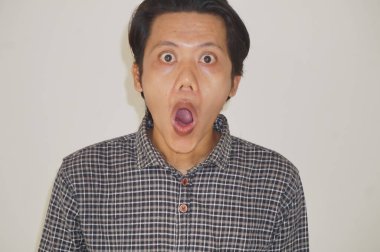 Beyaz arka planda izole edilmiş siyah gömlekli genç Asyalı adamın yüzü şaşırtıcıydı..