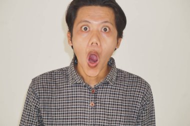 Beyaz arka planda izole edilmiş siyah gömlekli genç Asyalı adamın yüzü şaşırtıcıydı..