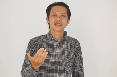 Asyalı genç adam ayakta duruyor ve gülümsüyor.