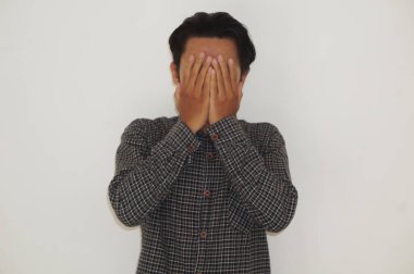 Siyah gömlekli genç Asyalı adam ellerini beyaz arka planda tutuyor..