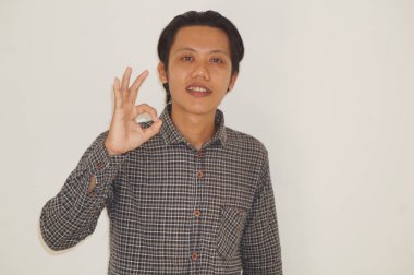 Siyah tişörtlü genç Asyalı bir adam tamam işareti gösteriyor.