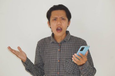 Genç Asyalı adam cep telefonu tutarken kafası karışık bir yüz ifadesi sergiliyor