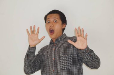 Beyaz arka planda siyah gömlekli Asyalı genç adamın şaşırmış ifadesi..