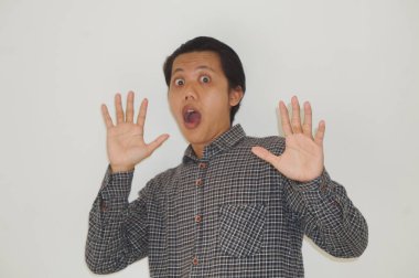 Beyaz arka planda siyah gömlekli Asyalı genç adamın şaşırmış ifadesi..