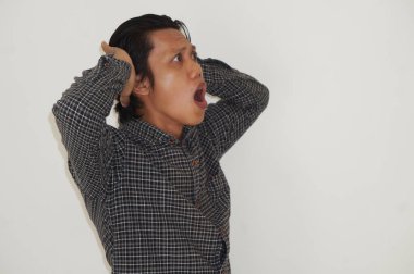 Beyaz arka planda siyah gömlekli Asyalı genç adamın şaşırmış ifadesi..