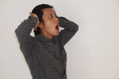 Beyaz arka planda siyah gömlekli Asyalı genç adamın şaşırmış ifadesi..