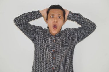 Beyaz arka planda siyah gömlekli Asyalı genç adamın şaşırmış ifadesi..