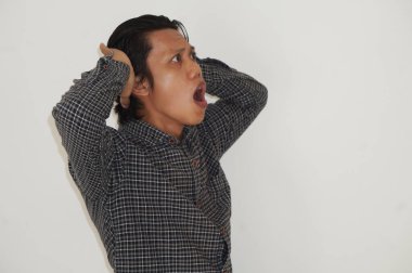 Beyaz arka planda siyah gömlekli Asyalı genç adamın şaşırmış ifadesi..