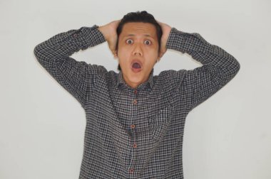 Beyaz arka planda siyah gömlekli Asyalı genç adamın şaşırmış ifadesi..