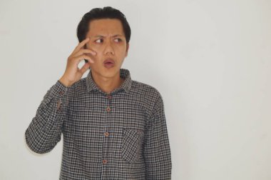 Siyah tişörtlü Asyalı genç bir adam bir şey düşünüyor..