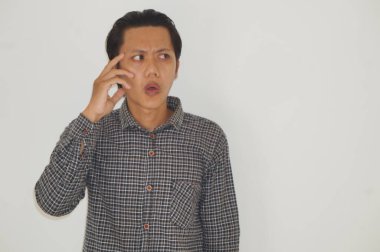 Siyah tişörtlü Asyalı genç bir adam bir şey düşünüyor..