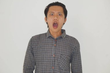 Beyaz arka planda siyah gömlekli Asyalı genç adamın şaşırmış ifadesi..