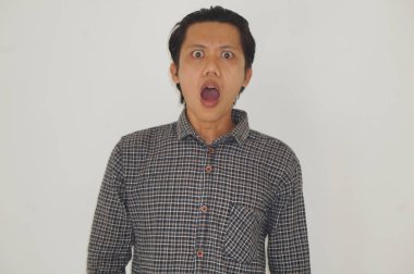 Beyaz arka planda siyah gömlekli Asyalı genç adamın şaşırmış ifadesi..