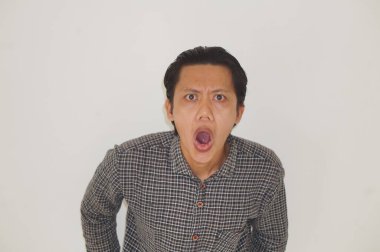 Beyaz arka planda siyah gömlekli Asyalı genç adamın şaşırmış ifadesi..