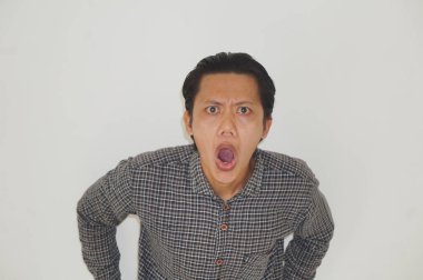 Beyaz arka planda siyah gömlekli Asyalı genç adamın şaşırmış ifadesi..