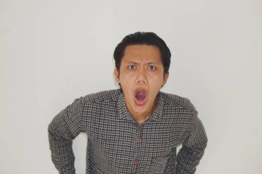 Beyaz arka planda siyah gömlekli Asyalı genç adamın şaşırmış ifadesi..