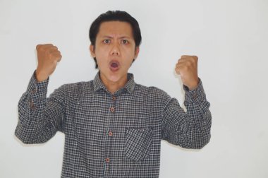 Mutlu Asyalı genç adam başarıyı ya da başarıyı kutlamak için kolunu kaldırıyor.