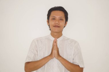 Beyaz elbiseli genç Asyalı Müslüman adam Ramazan 'da ve bayram kutlamalarında gülümsüyor.