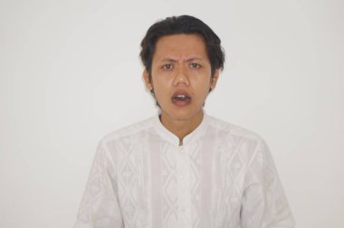 Beyaz arka planda izole edilmiş beyaz gömlekli Asyalı genç adamın şaşırmış ifadesi..