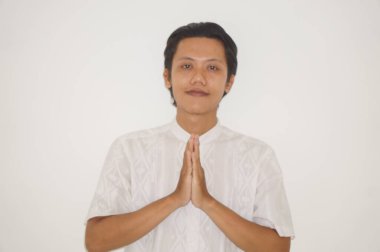 Beyaz elbiseli genç Asyalı Müslüman adam Ramazan 'da ve bayram kutlamalarında gülümsüyor.