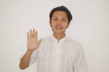 Beyaz gömlekli genç Asyalı yakışıklı adam gülümsüyor ve hareketlerini durduruyor.