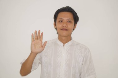 Beyaz gömlekli genç Asyalı yakışıklı adam gülümsüyor ve hareketlerini durduruyor.