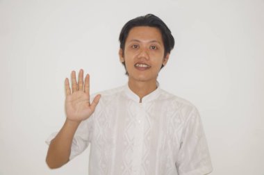 Beyaz gömlekli genç Asyalı yakışıklı adam gülümsüyor ve hareketlerini durduruyor.