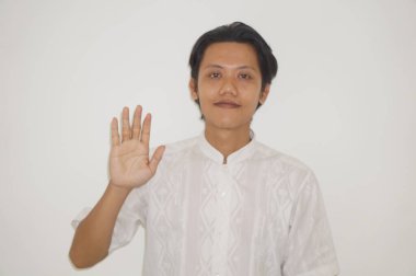 Beyaz gömlekli genç Asyalı yakışıklı adam gülümsüyor ve hareketlerini durduruyor.