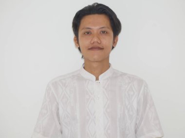 Genç Asyalı adam beyaz gömlekli kameraya bakıp gülümsüyor.