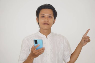 Genç Asyalı bir adam akıllı telefonu tutuyor ve elini kaldırıyor.