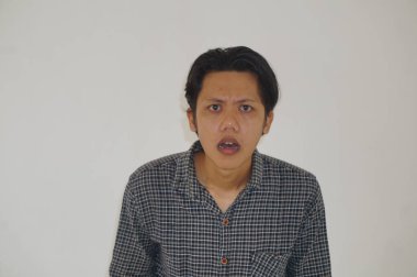 Beyaz arka planda siyah gömlekli Asyalı genç adamın şaşırmış ifadesi..